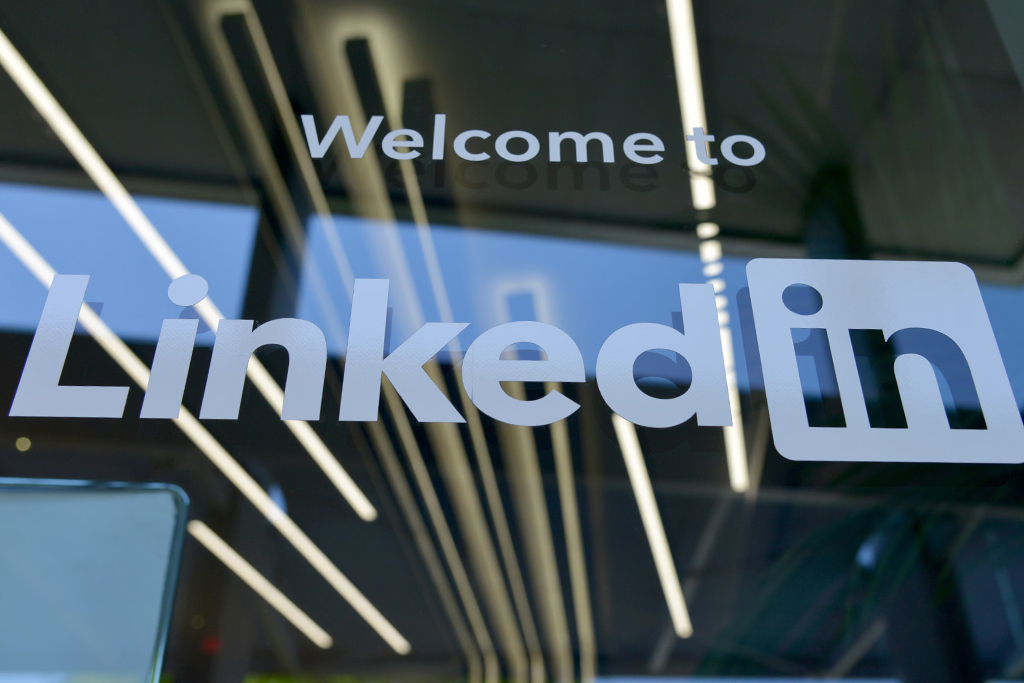 Glass facade of a building with 'Welcome to LinkedIn' signage and interior lights reflecting on the glass.