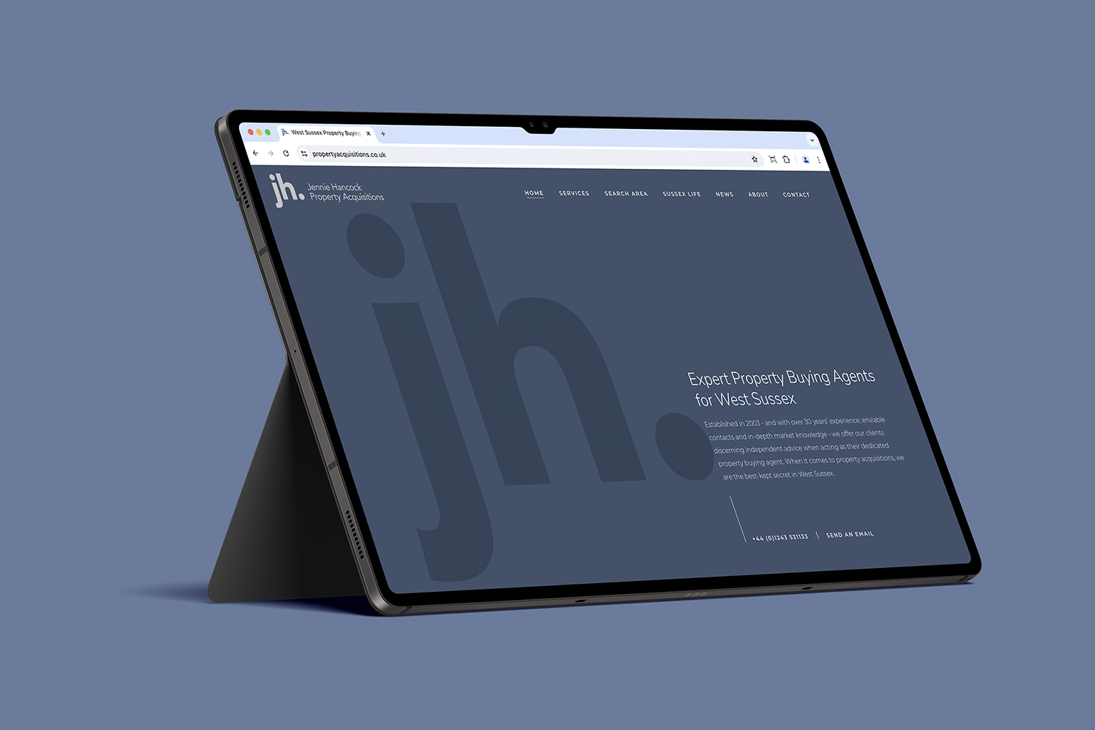 Tablet propped up against a modern gray background displaying a real estate website for property acquisitions.s